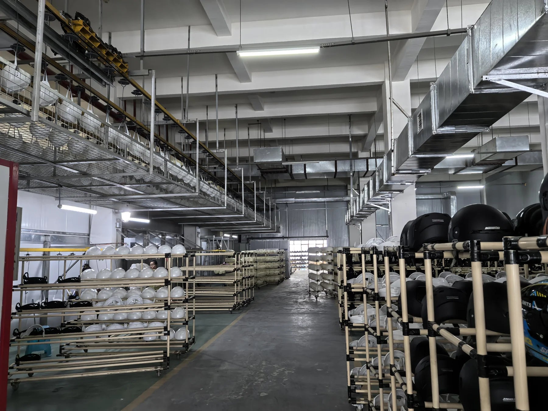 Wide photograph of helmet production racks and the factory workshop